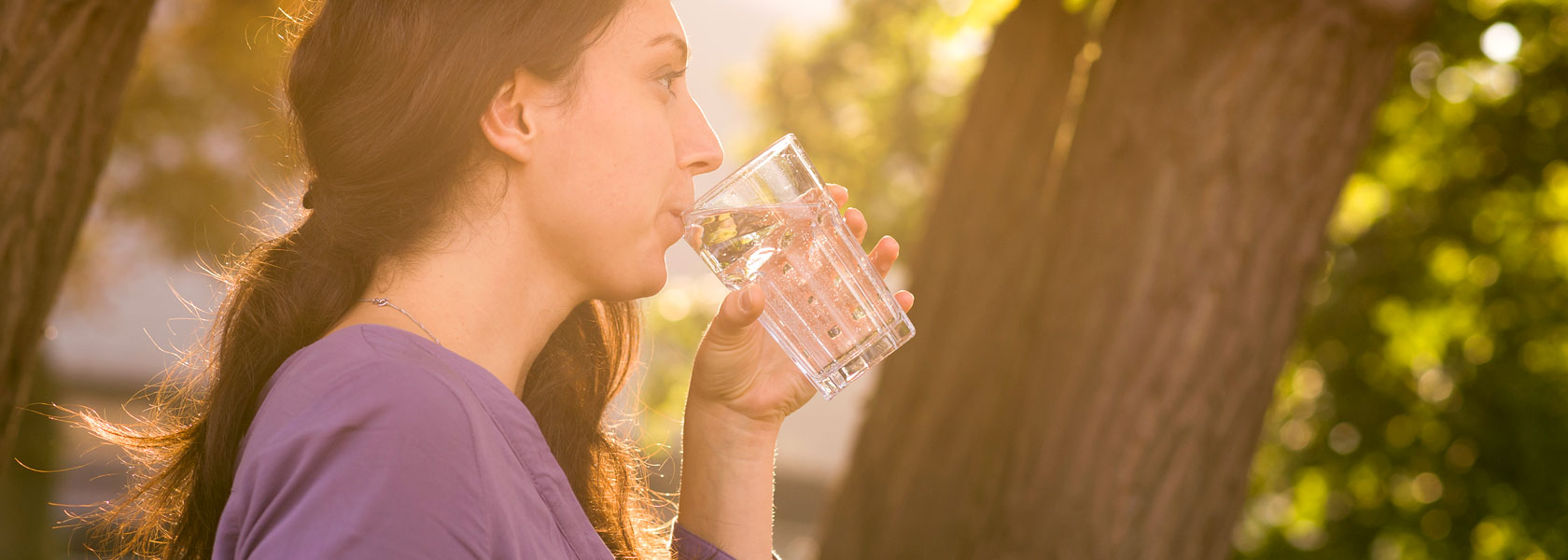 Eine Frau, die ein Glas Wasser im Wald trinkt