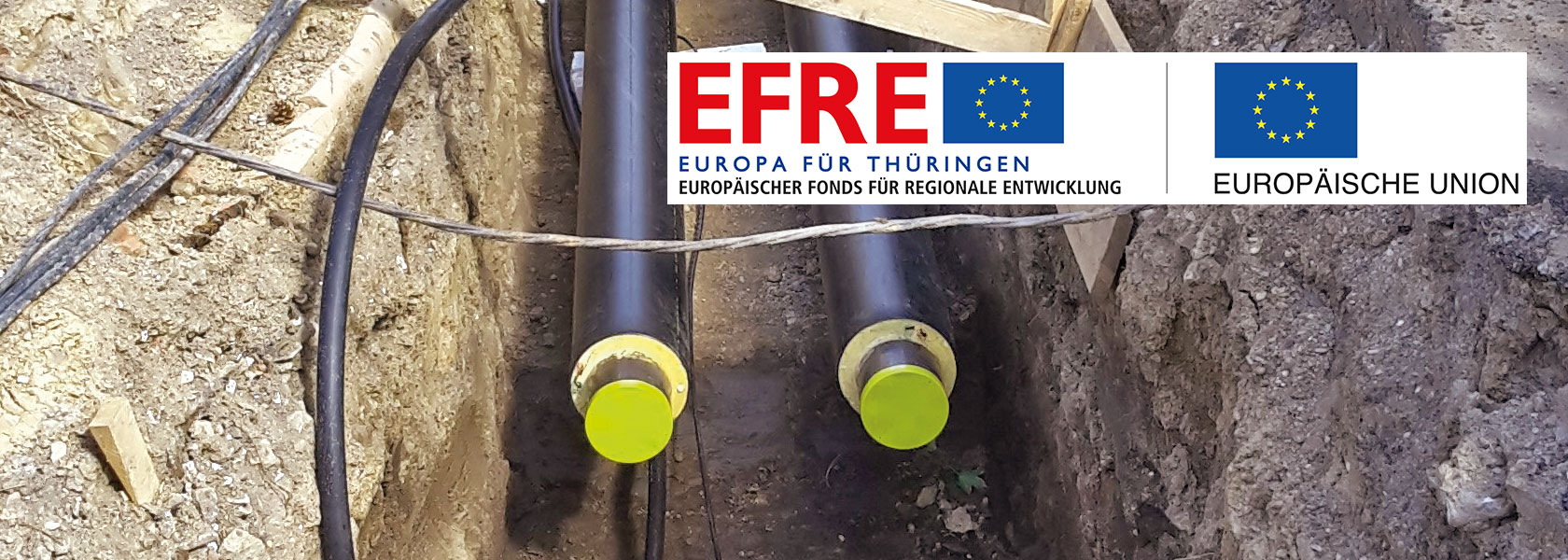 Graben mit zu verlegenden Rohren für Fernwärme in Erfurt mit EFRE-Plakette
